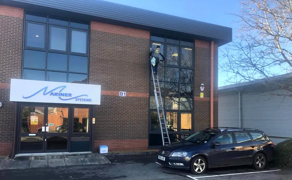 Window cleaner on a ladder at a commercial office building