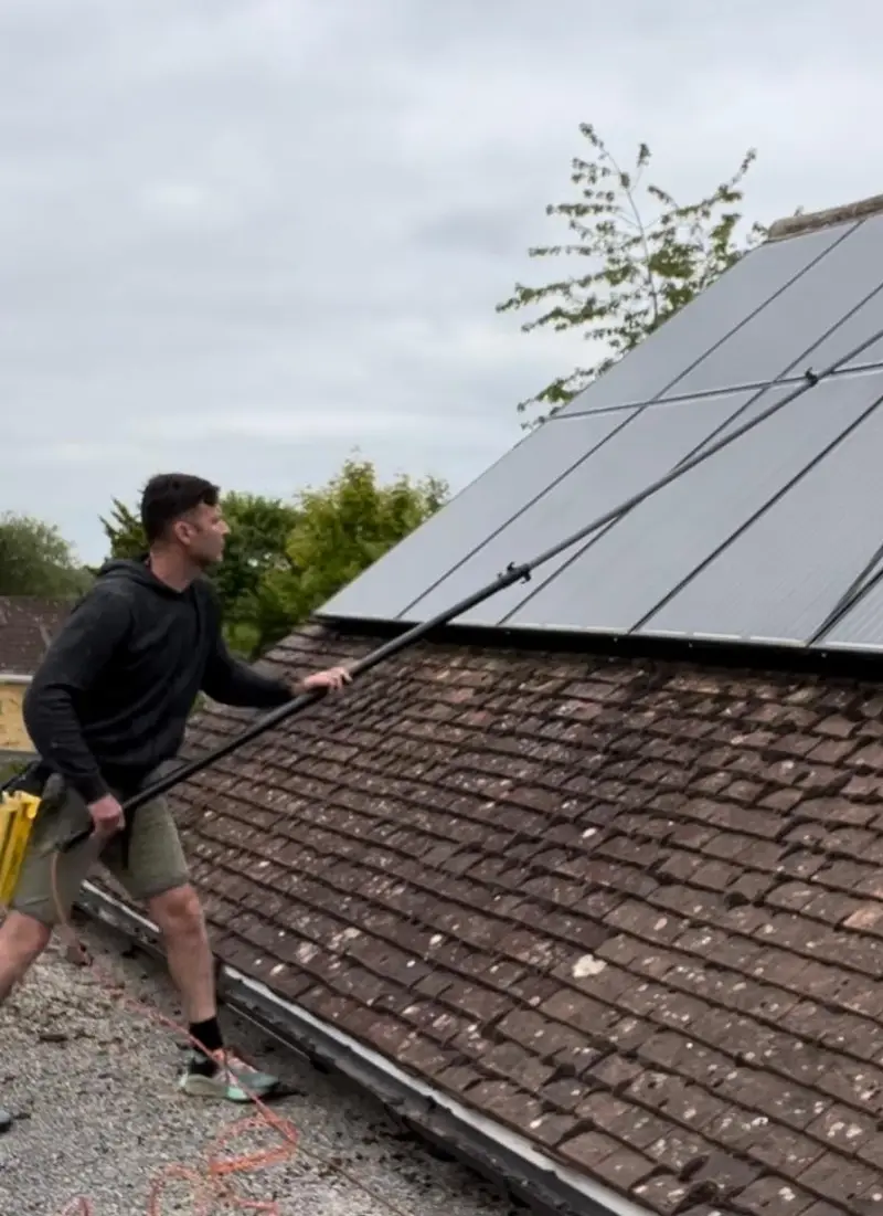Cleaning roof-mounted solar panels with a pole